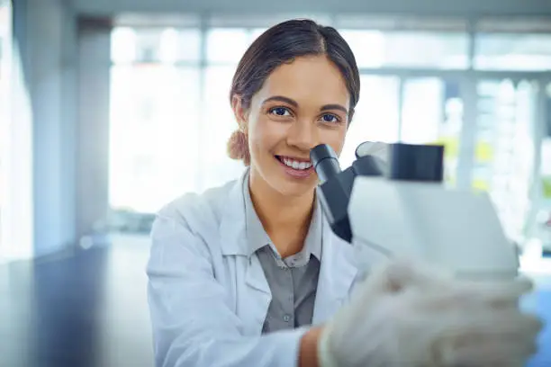 Portrait of a young scientist using a microscope in a lab