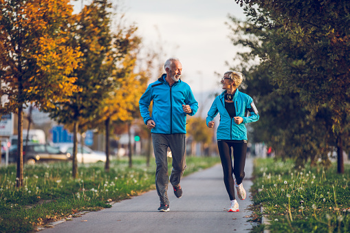 Senior couple in sports clothing jogging together. Front View.