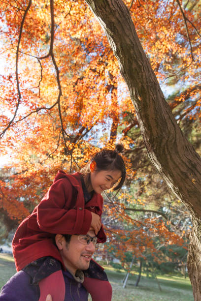 istock Young family enjoying autumn under Japanese maple tree 889457596