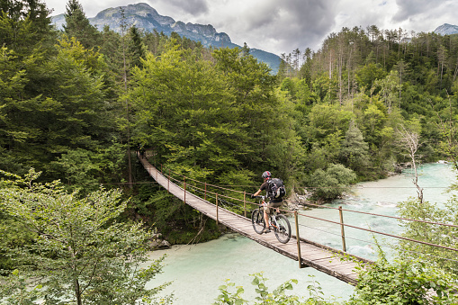 Mountainbiker hombre está cruzando un puente colgante en Eslovenia. photo