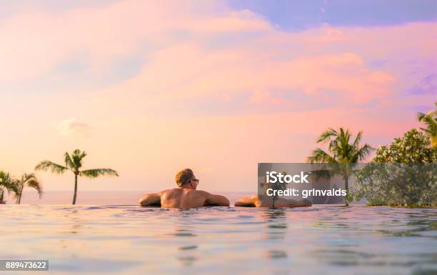 Pareja Mirando La Hermosa Puesta De Sol En La Piscina Foto de stock y más banco de imágenes de Vacaciones - Viaje