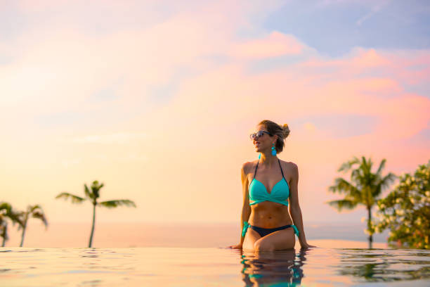 istock Girl sitting on edge of infinity pool 889473682