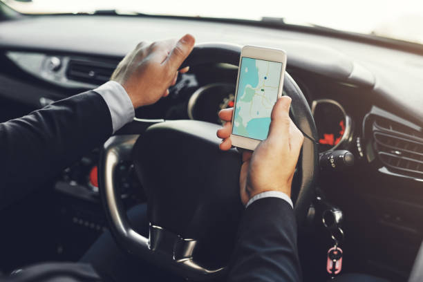 Getting around with the help of technology Closeup shot of an unrecognizable businessman using his cellphone while driving tracker stock pictures, royalty-free photos & images