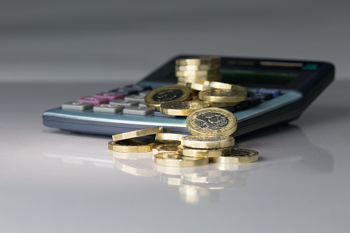 Shot close up in the studio on a reflective surface in a grey gradient background environment. Stacks and fallen pound coins.