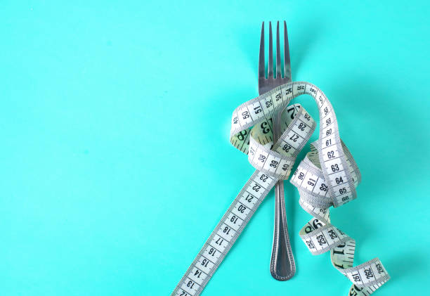 istock Fork with measuring tape. Dieting concept. On blue. 889486998