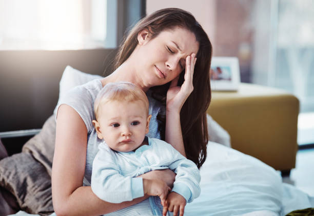 Headache at the wrong time Shot of a mother and her baby boy at home postpartum depression stock pictures, royalty-free photos & images