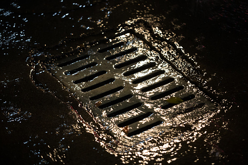 the sewer with rain water at night illuminated with street light