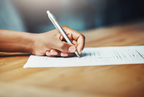 Making her mark Cropped shot of a woman filling in some paperwork at a desk form filling stock pictures, royalty-free photos & images