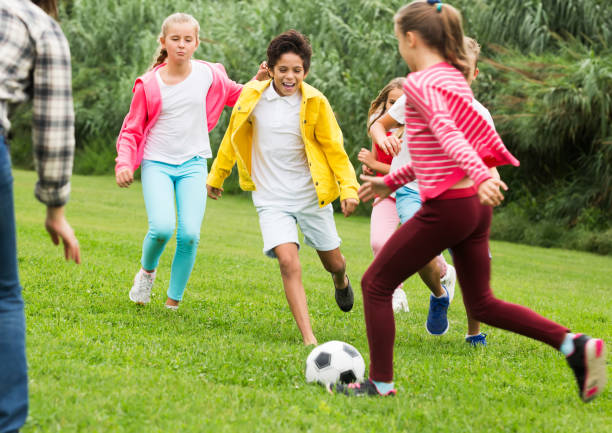 istock Kids playing football in park 889513068