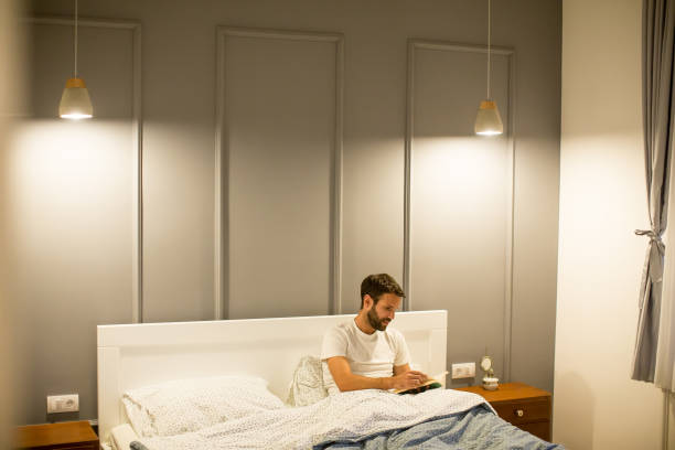 istock Young man reading book in bed 889514000