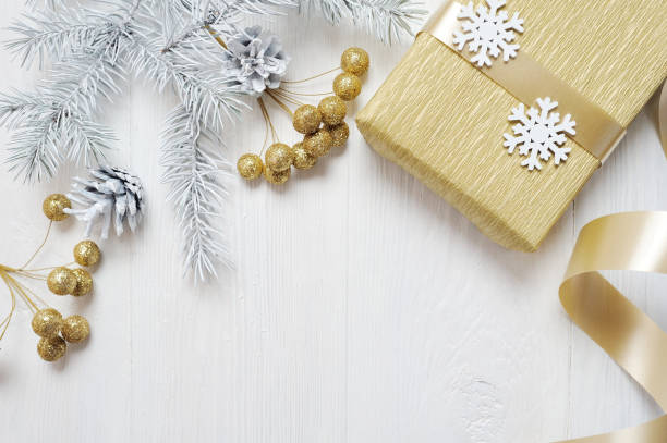 istock Mockup Christmas gift gold bow and tree cone, flatlay on a white wooden background, with place for your text 889524570