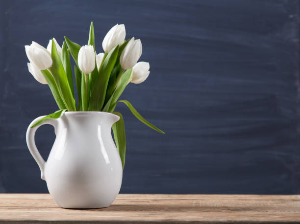 木製のテーブルに古風素朴な花瓶鍋にチューリップの花束。ぼかしの背景に白い水差しの光の色の花です。 - cut flowers bouquet flower flower arrangement ストックフォトと画像