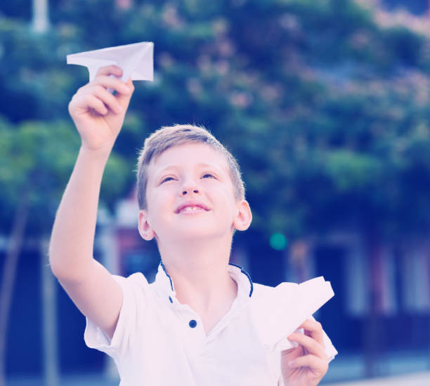 istock boy playing with paper airplane 889525212