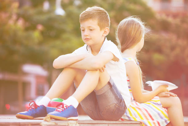 istock sad boy sitting back to friend outdoor 889525288