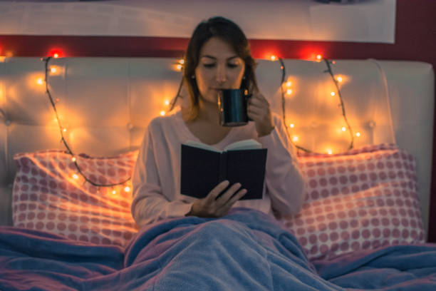istock Beautiful woman reading in bed before sleep 889529686