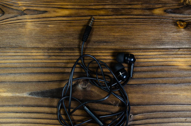 istock Black earphones on wooden table. Top view 889531050