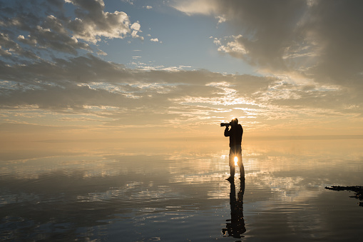 Photographer  having fun walking on salt lake at sunset