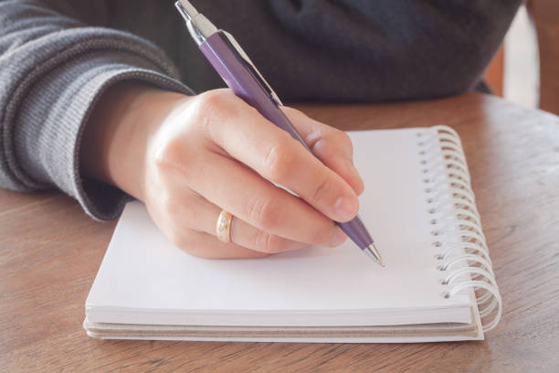 istock Close-Up Of Hand Writing With Pen In Book 889537590