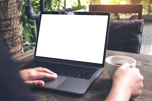 istock Mockup image of a woman using laptop with blank white screen while drinking coffee on wooden table at outdoor 889573972