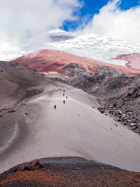 Backpackers climbing Cotopaxi volcano along a pyroclastic rocks hiking trail, Ecuador