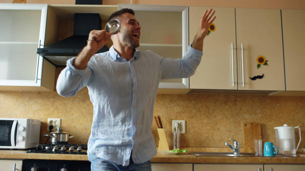 istock Attractive young funny man dancing and singing with ladle while cooking in the kitchen at home 889587382