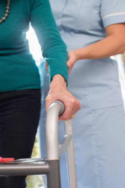istock Senior Woman's Hands On Walking Frame With Care Worker In Background 889592056