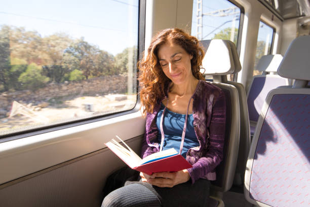 istock happy woman in train reading book 889605772