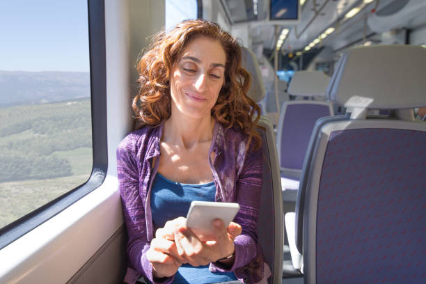 istock smiling woman in train touching smartphone 889605948