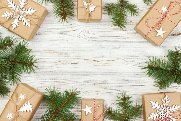istock creative arrangement christmas frame. craft gift boxes and green branches on white wooden background. flat lay, top view, cope space 889609612