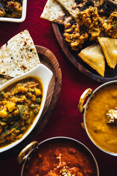 istock Indian feast with butter chicken, chicken tandoori, lamb curry, vegetable curry, samosas, pakoras, bhajis, naan bread and basmati rice on a table. North Indian food 889610328