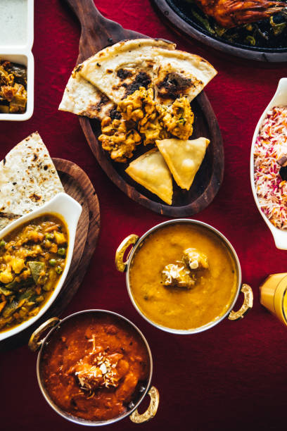 fiesta india con mantequilla pollo, tandoori de pollo, curry de cordero, curry vegetal, samosas, pakoras, bhajis, pan naan y basmati arroz sobre una mesa. comida de la india del norte - punjab fotografías e imágenes de stock