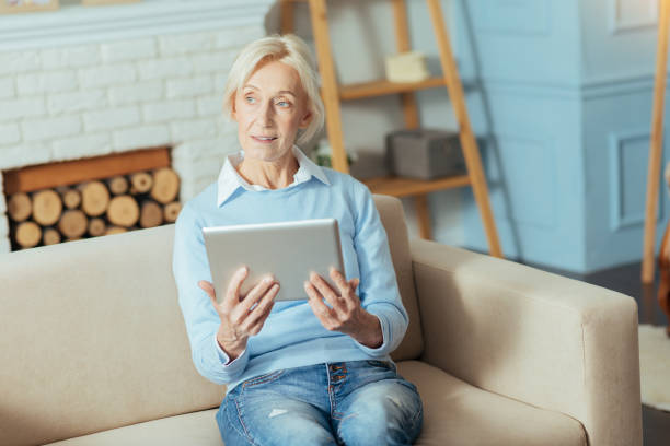 istock Smart calm pensioner sitting with a modern gadget and thinking 889615142