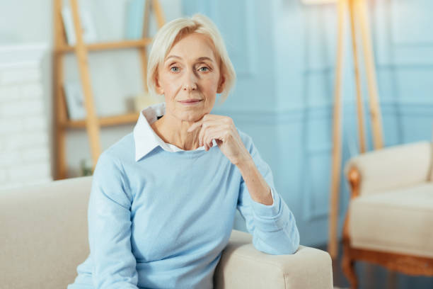 istock Cute aged woman sitting on a sofa and waiting for her relatives 889615270