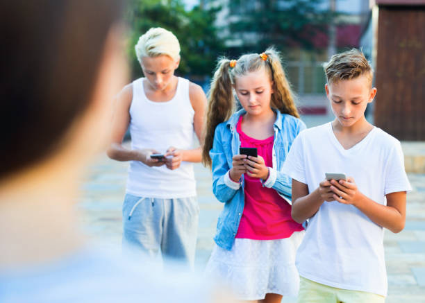 istock Three children keened on mobile phones during joint walk around city 889615610