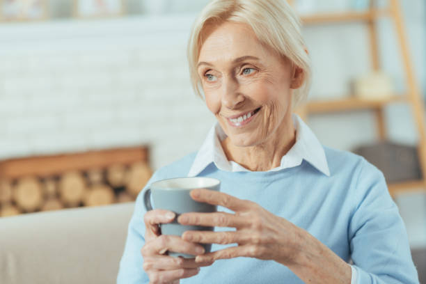 istock Cheerful senior woman smiling while holding her favorite mug 889615740