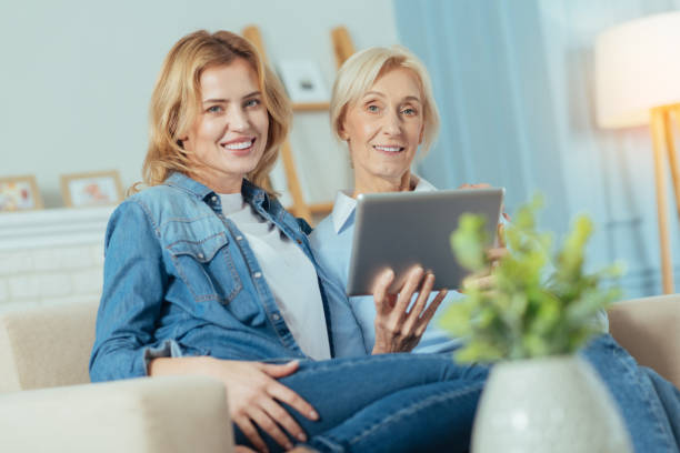 istock Cheerful women sitting on a sofa and holding a modern tablet 889618786