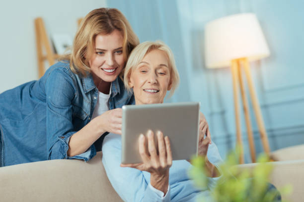 istock Smiling woman teaching her grandmother how to use a modern device 889619042