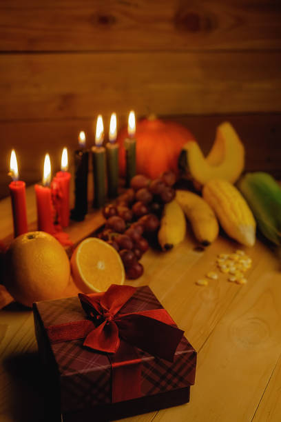 クワンザ休日の概念は、7 キャンドル赤、黒、緑、ギフト ボックス、カボチャ、トウモロコシ、木製の机と背景にフルーツを飾る。 - kinara ストックフォトと画像