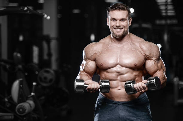 istock Brutal strong bodybuilder athletic men pumping up muscles with dumbbells 889641628