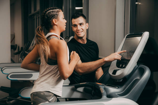 mujer joven en el gimnasio jogging - gym machine smiling coach fotografías e imágenes de stock