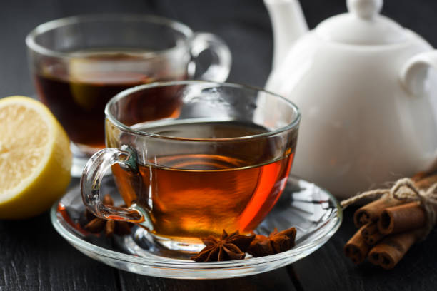 istock Cup of hot black tea with lemon, cinnamon and star anise on black rustic background 889654434