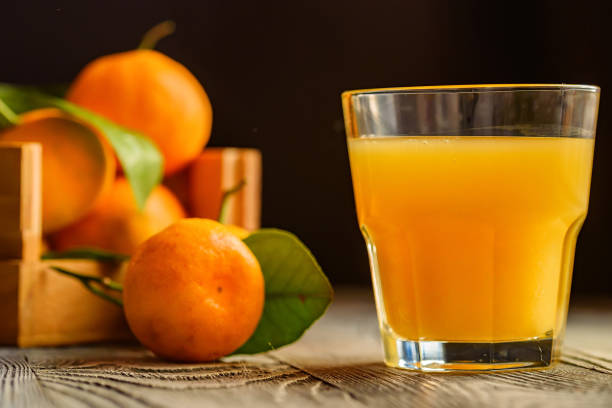 istock Glass of fresh juice and mandarins on table 889655150