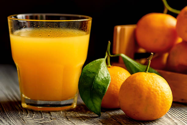 istock Glass of fresh juice and mandarins on table 889657284