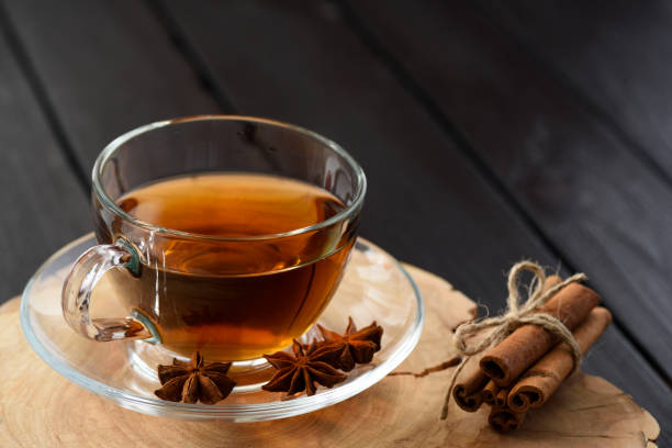 istock Cup of black tea with spices on wood slab copyspace 889657460