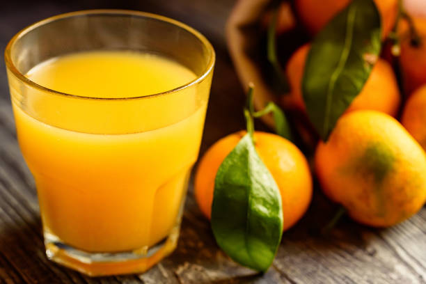istock Glass of fresh juice and mandarins on table 889657478