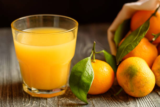 istock Glass of fresh juice and mandarins on table 889657566