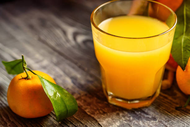 istock Glass of fresh juice and mandarins on table 889657652