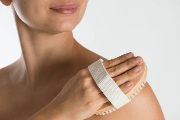Woman scrubbing her skin with a scrubbing brush.