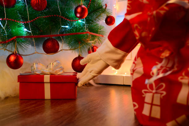 istock Santa delivering presents under Christmas tree 889665074