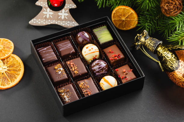 Set of coloful luxury handmade bonbons in box on christmas background Assortment of colorful handmade chocolate candies in black box with christmas decorations. Exclusive luxury bonbons. Product concept for chocolatier chocolate pieces stock pictures, royalty-free photos & images